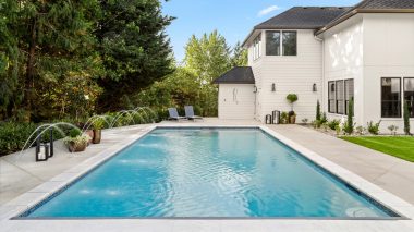 Beautiful home exterior and large swimming pool on sunny day wit